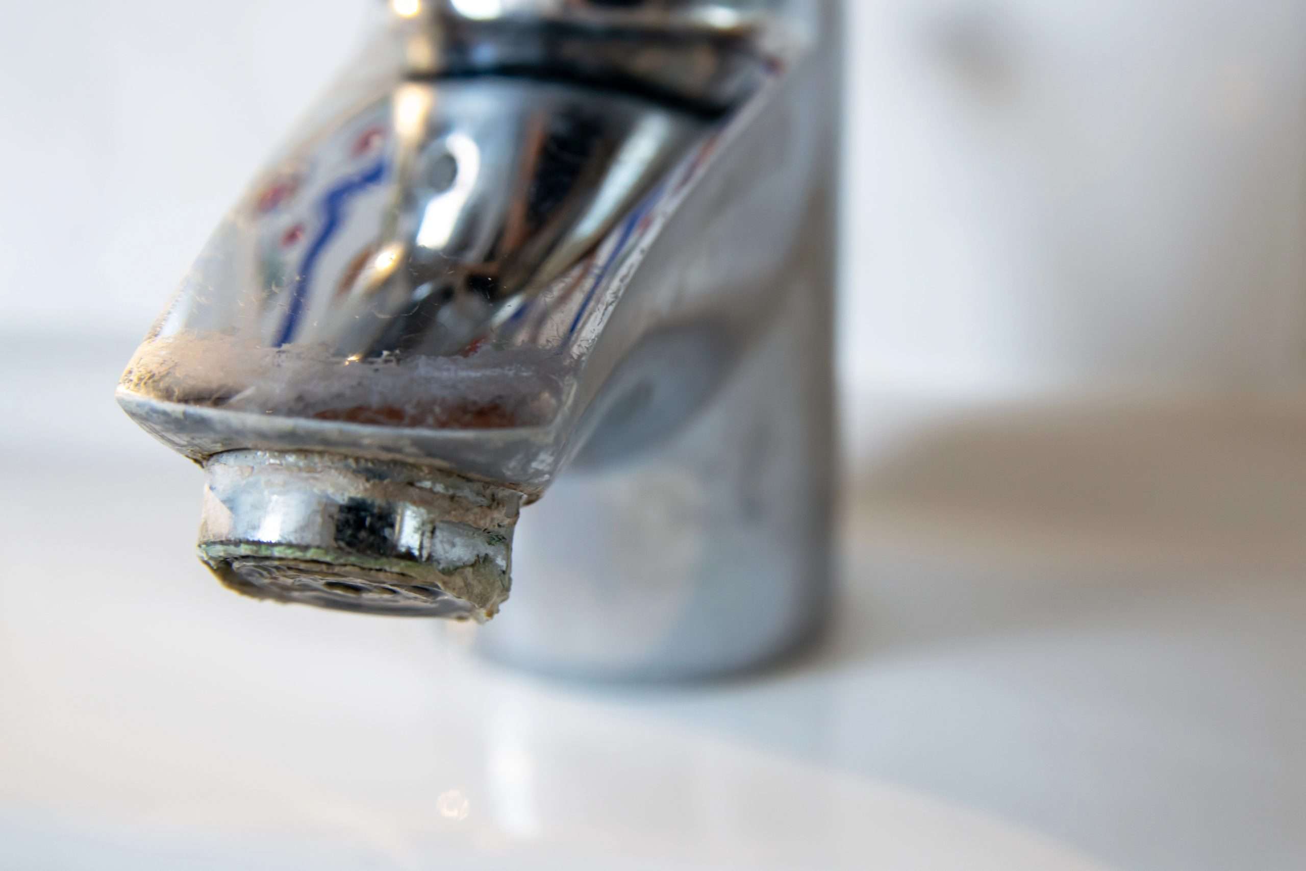 A bathroom water fixture with hard water buildup and hard water stains